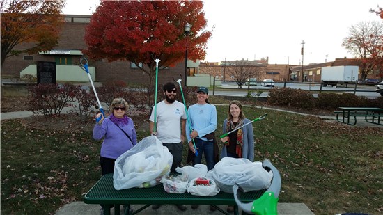 3 women and 1 man standing behind trash collected in a park