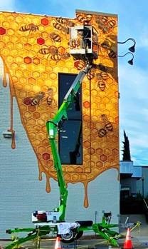 man painting bee mural