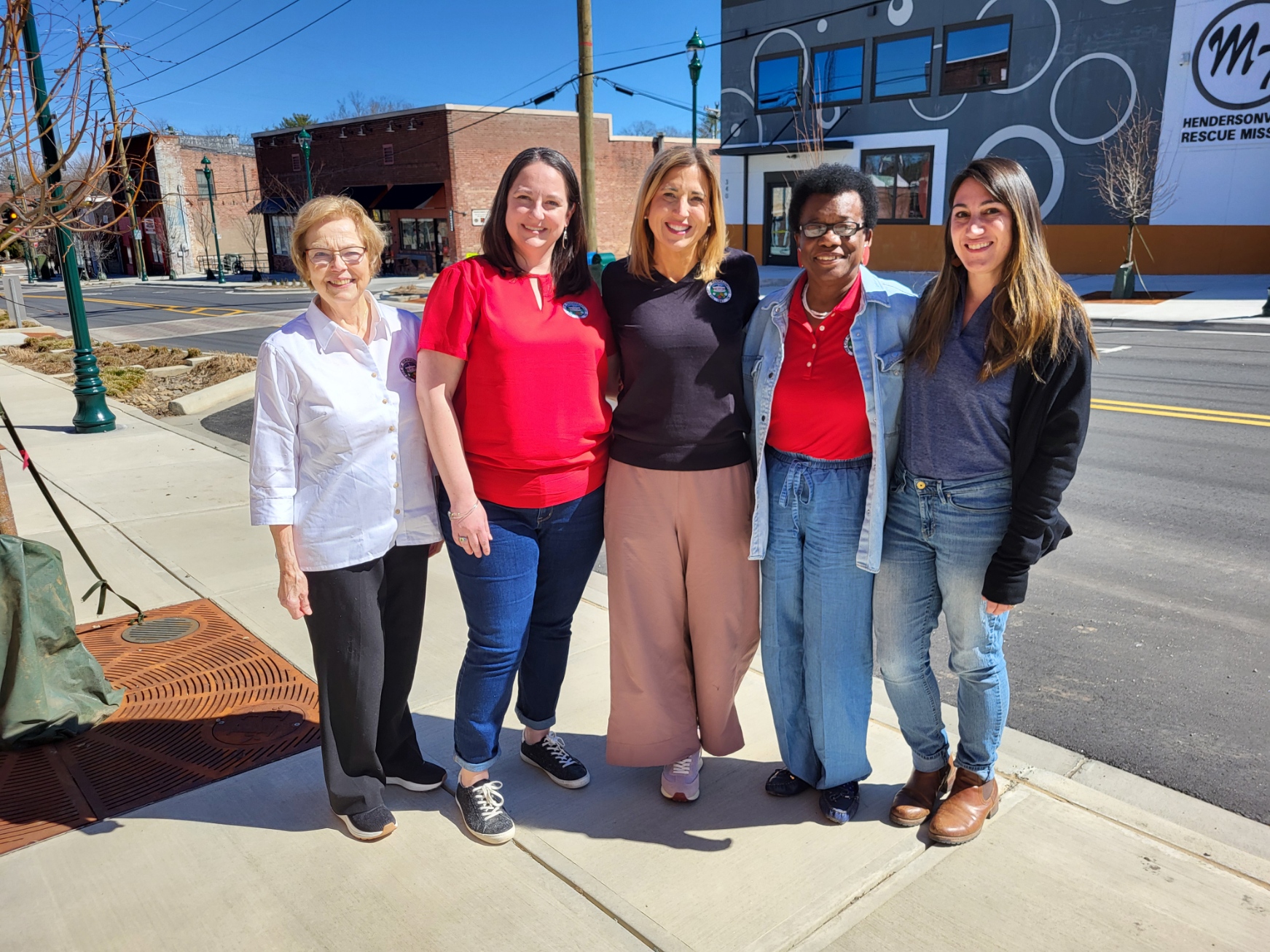 5 female council members smiling and standing on a sidewalk