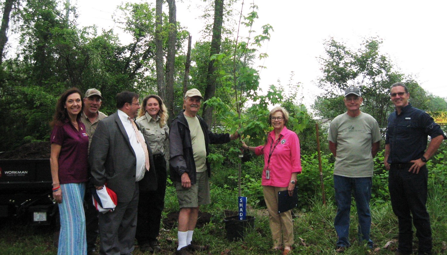 Mayor and man holding a tree that was planted with people standing around them