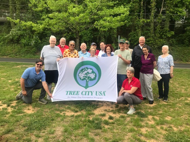 A group outside holding a large Tree City USA banner