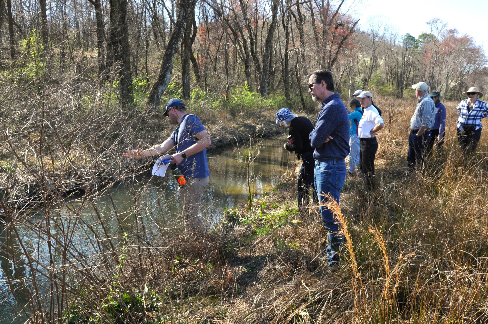 People standing along a streambank