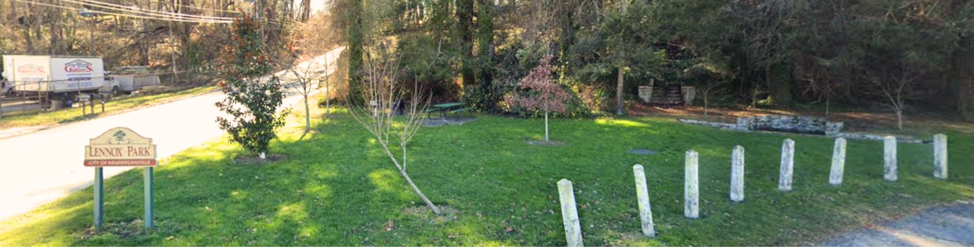 Lennox Park sign with trees and picnic table in distance