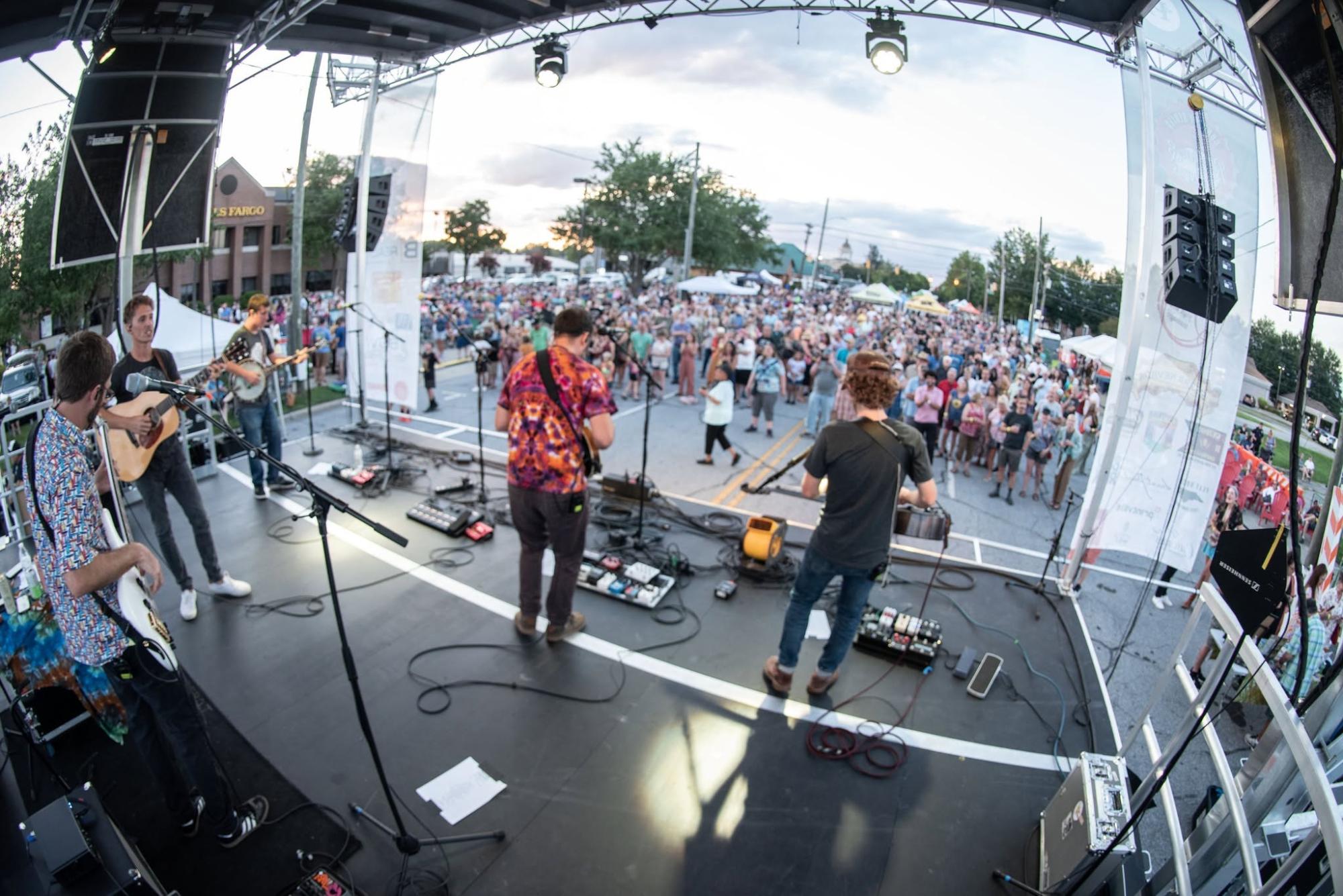 bands playing on a stage in front of an outdoor crowd